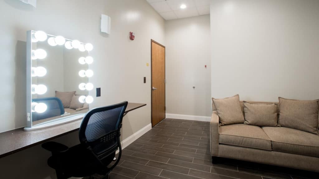 Private green room at Annex 302 with a lit makeup mirror, counter and sofa