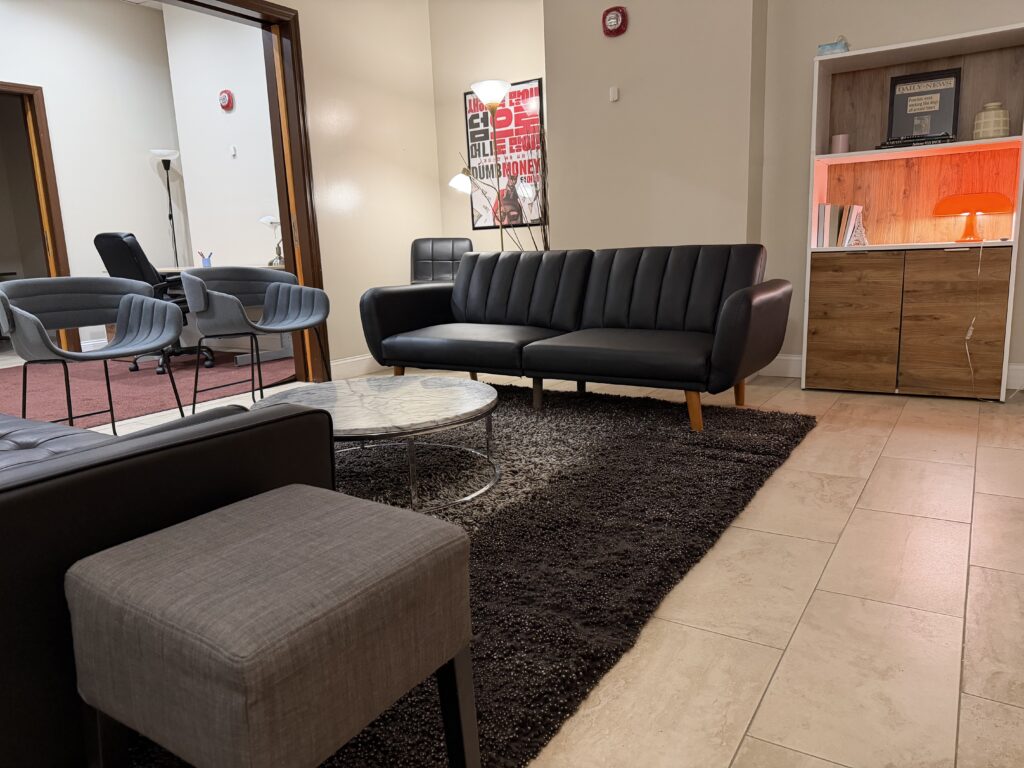Client lounge at Annex 302 with a leather sofa, armchairs and coffee table on a shag rug